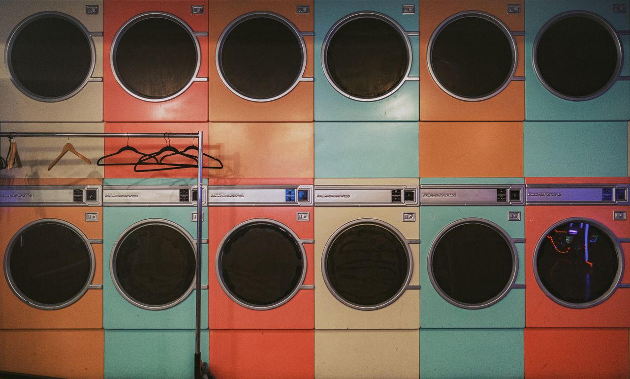 Colorful row of vintage laundry machines with hangers in a laundromat.